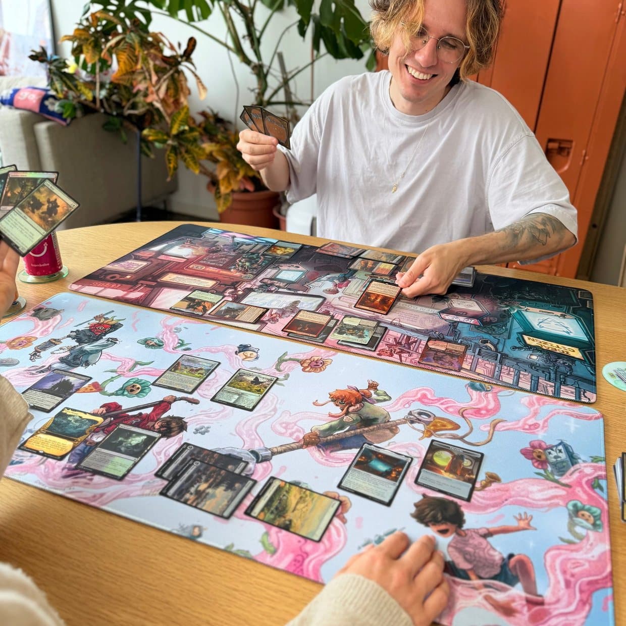 A person at a desk covered by the printed Entering Rift deskmat, with trading cards laid out across it