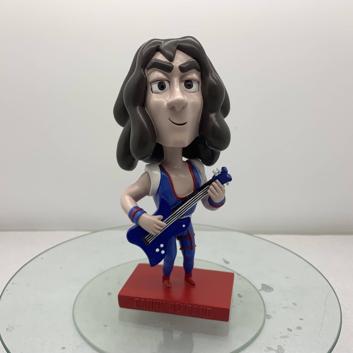A Ninja Sex Party bobblehead figure holding a blue guitar, standing on a round base